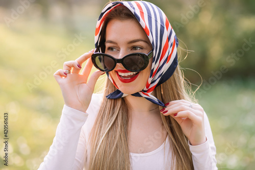 Young woman in retro style. Sunglasses and silk scarf. Sixties s