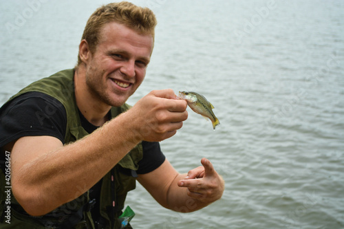 Photography Man holding very small fish, shore fishing