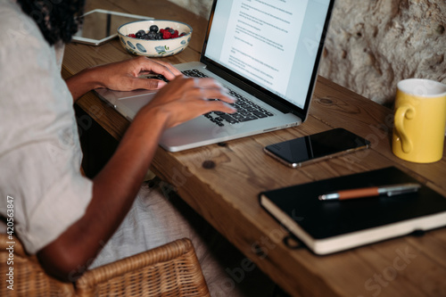 Crop black journalist writing article at home