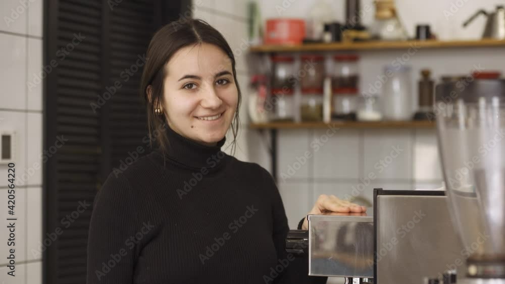 happy barista approaches his coffee machine and looks at the camera with a sweet look happy barista approaches his coffee machine and looks at the camera with a sweet look