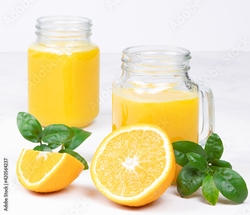 Orange juice and green leaves on a white background.A glass of orange juice and orange fruit. Healthy food. Vegan food. Diet and proper nutrition.
