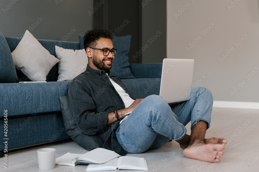 Cheerful black student using laptop on floor Cheerful black student using laptop on floor