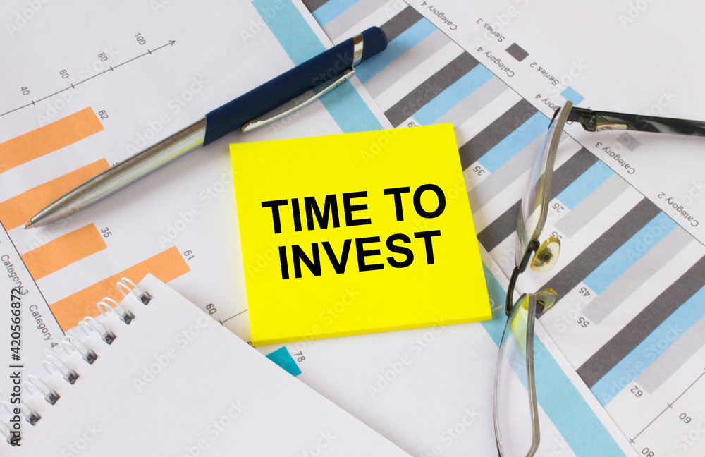 Yellow sticker with text Time To Invest lies on financial charts with pen and eyeglass Yellow sticker with text Time To Invest lies on financial charts with pen and eyeglass