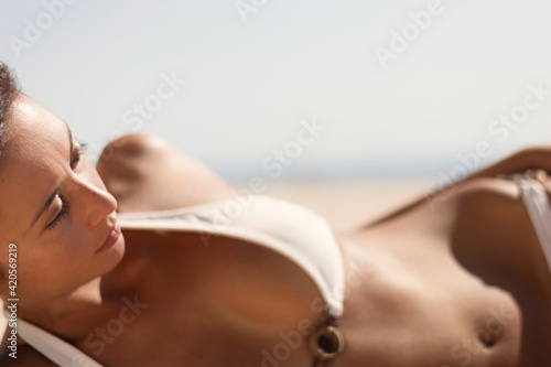 Young woman portrait laying on the sand for a tan at the beach