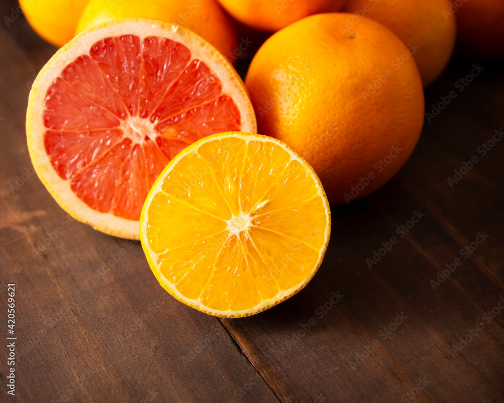 close up of ripe orange and grapefruit slices and several whole oranges on brown rustic wooden table with copy space close up of ripe orange and grapefruit slices and several whole oranges on brown rustic wooden table with copy space