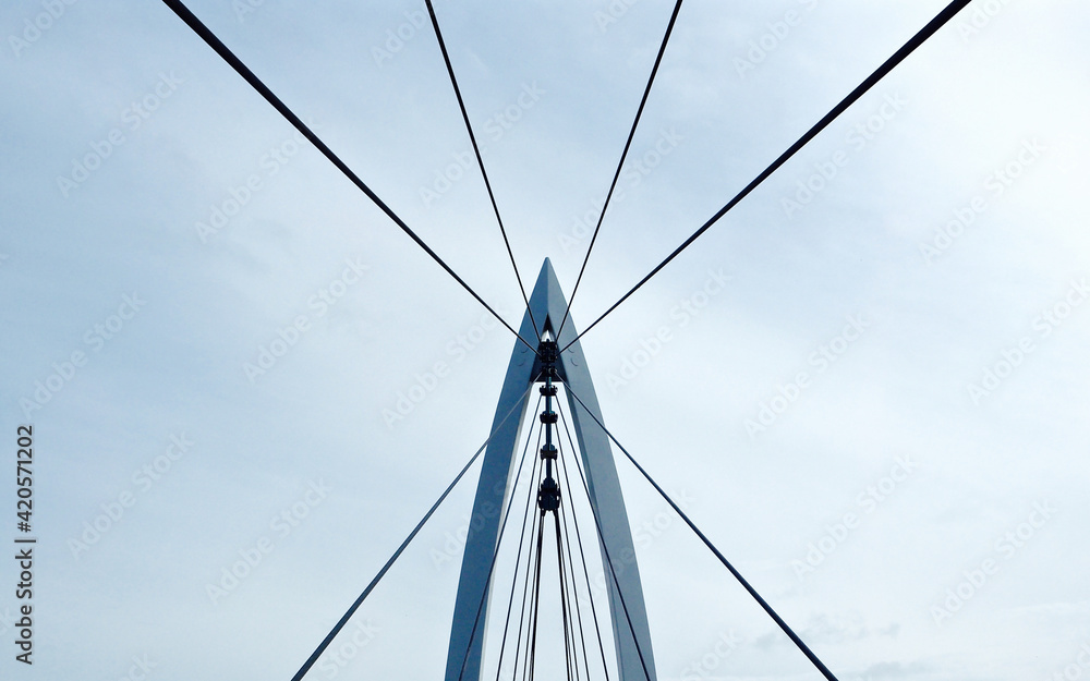 Contemporary style pedestrian suspension bridge over the Arkansas River taken in Wichita, KS where people can walk across the bridge with views of the river and city Contemporary style pedestrian suspension bridge over the Arkansas River taken in Wichita, KS where people can walk across the bridge with views of the river and city