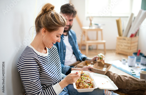 Fényképezés Couple eating lunch indoors at home, relocation, diy and food delivery concept