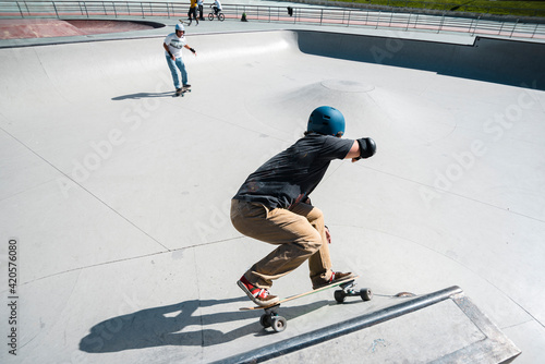 Front view of mid aged man skateboarder in his forties performing stunt on ramp at skate park with safety helmet photo