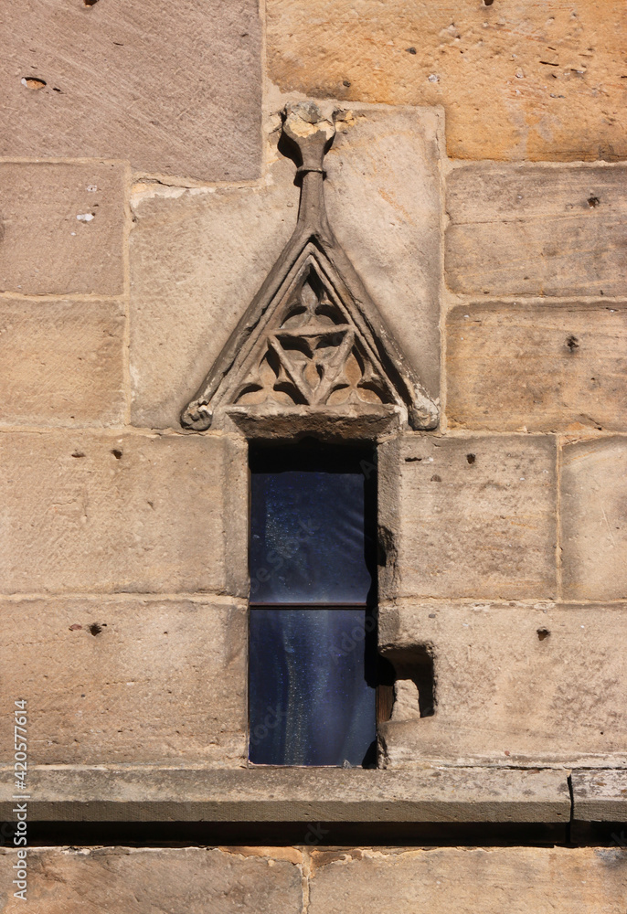 Small gothic window with triangular wimperg gable at Schlosskirche church in the old town of Bad Dürkheim in Germany