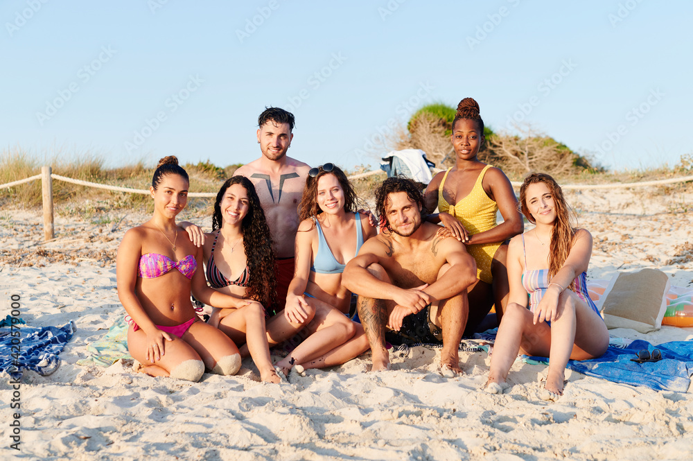 Smiling group of friends sitting on a beach Smiling group of friends sitting on a beach