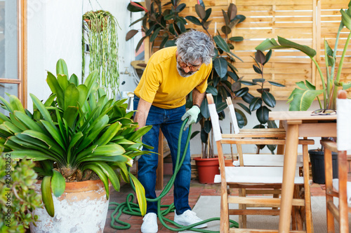 Senior man watering the plants in a terrace