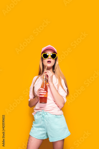 Lovely woman with cold drink standing on yellow background © zamuruev