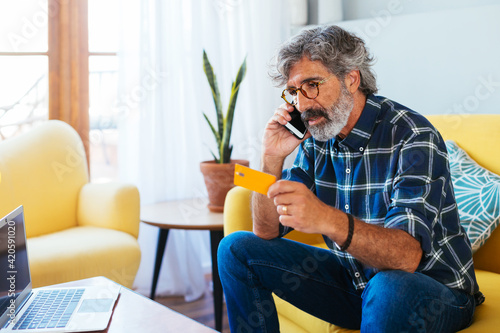 Adult man talking by phone at home office