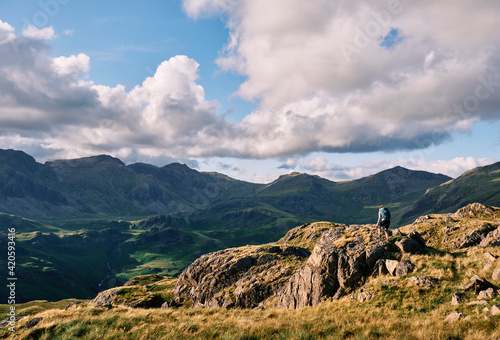 Female walker on Hard Knott looking towards Sca Fell at sunset. Lake District, Cumbria, UK. photo