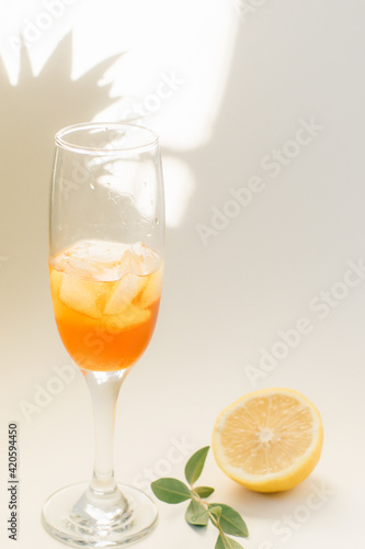 Cold refreshing drink with lemon orange slices by the glass on white background on directly sunlight with shadows