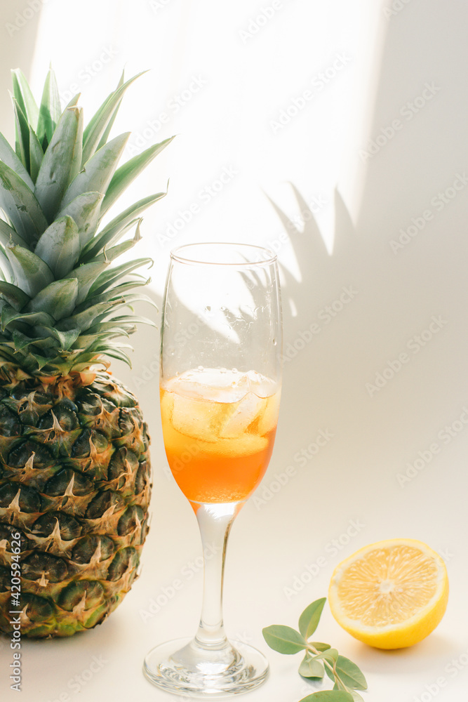 Cold refreshing drink with lemon orange slices by the glass on white background on directly sunlight with shadows Cold refreshing drink with lemon orange slices by the glass on white background on directly sunlight with shadows