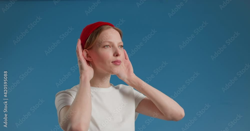 Happy Woman Putting Both Hands On Her Ears Smiling While Listening To The Music Against blue Studio Background - Half-Body Shot Happy Woman Putting Both Hands On Her Ears Smiling While Listening To The Music Against blue Studio Background - Half-Body Shot
