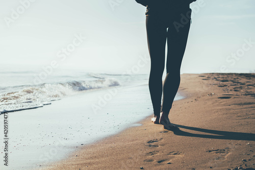 Joven mujer paseando por la orilla del Mediterráneo mojando sus pies en el mar.  photo