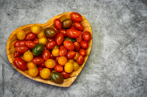 Cherry tomatoes in a wooden heart-shaped plate. Top view