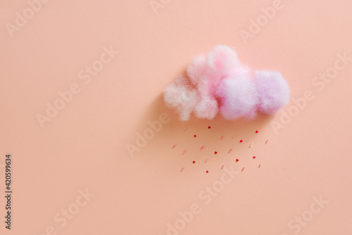 Cotton ball cloud rain sugar candy sprinkle hearts red pink on pink sky background