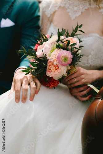 bride holding a pastel pink colored wedding bouquet and groom holding hand tender on knee of bride photo