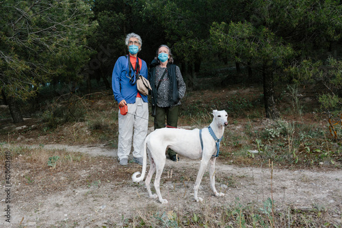 Elderly Man and woman with facemark and dog outdoors photo