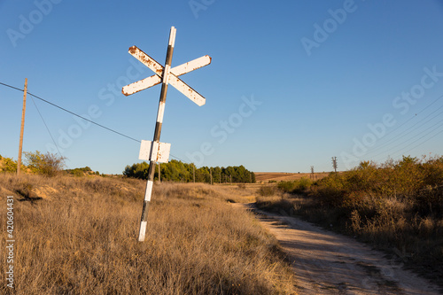 an old Spanish railroad crossing traffic sign on a dirt road in summer - San Esteban de Gormaz, province of Soria, Castile and Leon, Spain photo