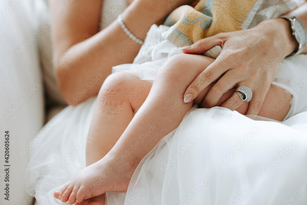 close up of baby sitting on bride's lap for bottle close up of baby sitting on bride's lap for bottle