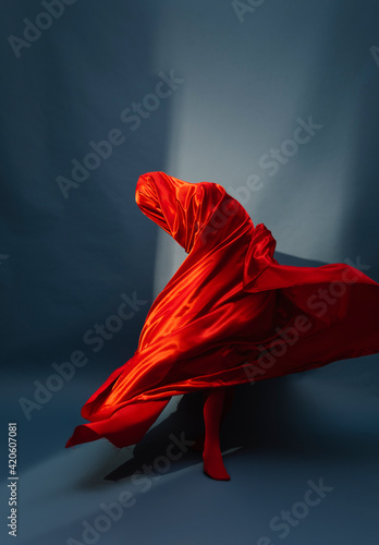 woman playing with red silk fabric on blu background photo