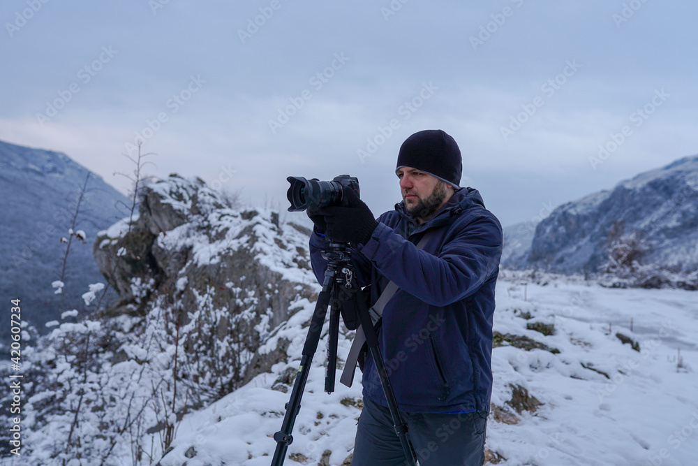 Photographer standing on mountain viewpoint on snowy day and taking picture