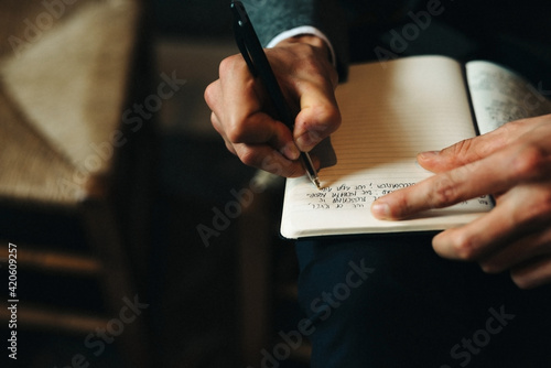 male hand writing down words in a notebook