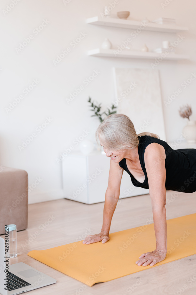 Elderly sportswoman doing plank exercise during online workout Elderly sportswoman doing plank exercise during online workout