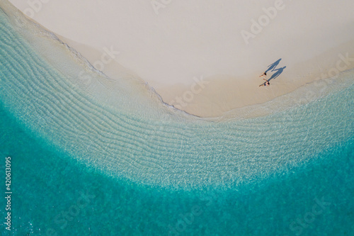 A Couple walking on a maldivian beach seen from above