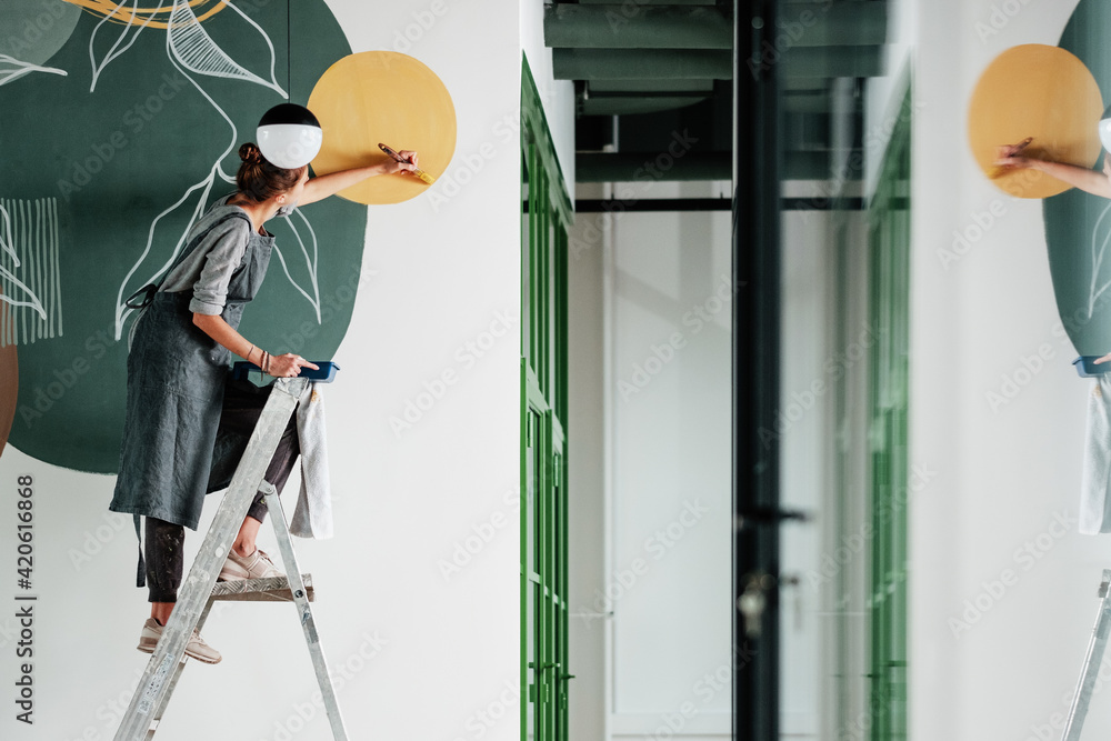 © Milles Studio/Stocksy - Young female painting on wall in new apartment