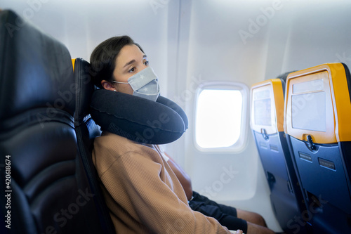 Woman With Mask Sitting On A Plane. photo