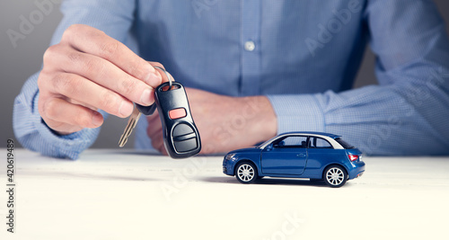 man holding key and car model