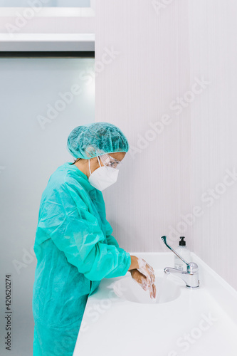 Surgeon woman in medic uniform washing hands in clinic photo