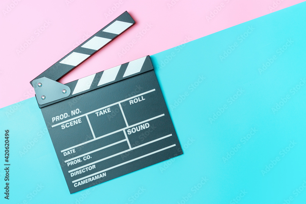 The clapperboard on pink and blue background close-up, top view.