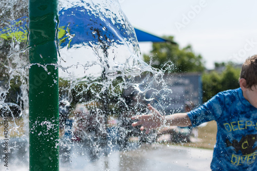 Child dragging hand through a cascade of water at a splash pad in summer