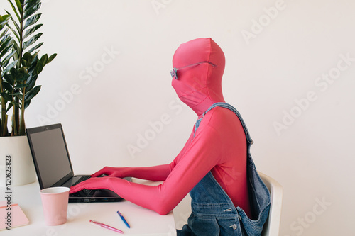 Unrecognizable person in colorful outfit working on laptop
