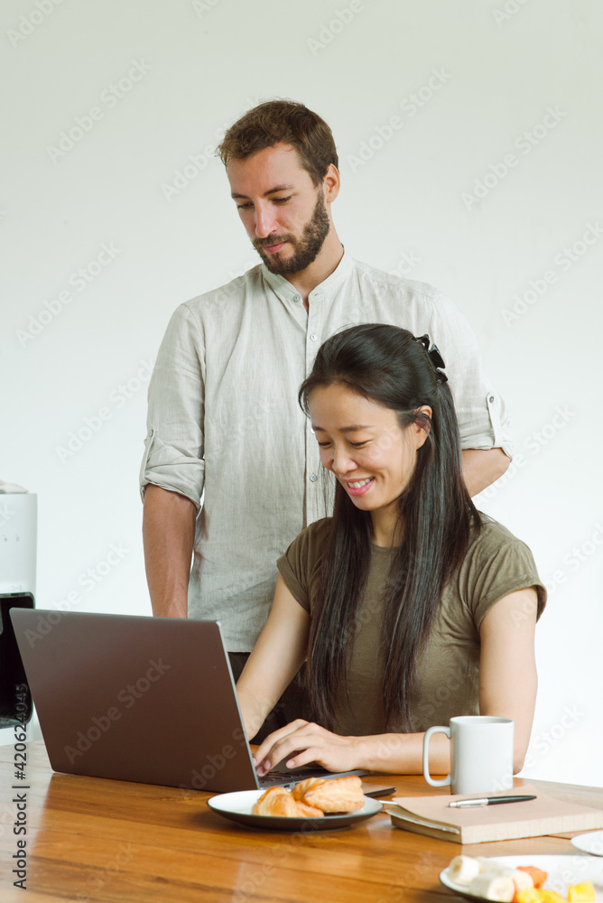 European guy helping chinese woman with laptop work European guy helping chinese woman with laptop work