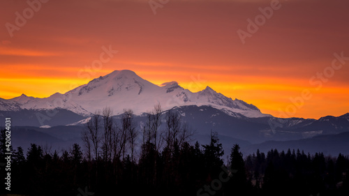 Orange and Yellow Sky at Sunrise in the Fraser Valley of British Columbia, Canada with Mount Baker, a dormant volcano in Washington State, on the horizon © hpbfotos