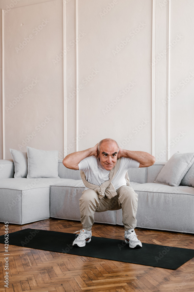 Active senior man doing squats at home Active senior man doing squats at home