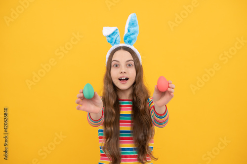 feeling a surprise. childhood happiness. child in rabbit ears hold painted eggs. time for fun.