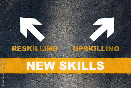 New skills development concept and changing skill demand idea. New skills written on yellow line with reskilling and upskilling with white arrow on asphalt road photo