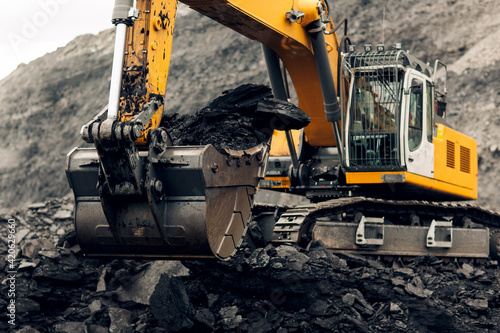 Excavator loads coal into the back of a heavy mining dump truck. Open pit coal mining.