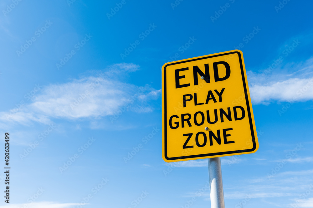 Naklejka premium End play ground zone yellow traffic road sign and black letters under bright blue sky background with copy space for text