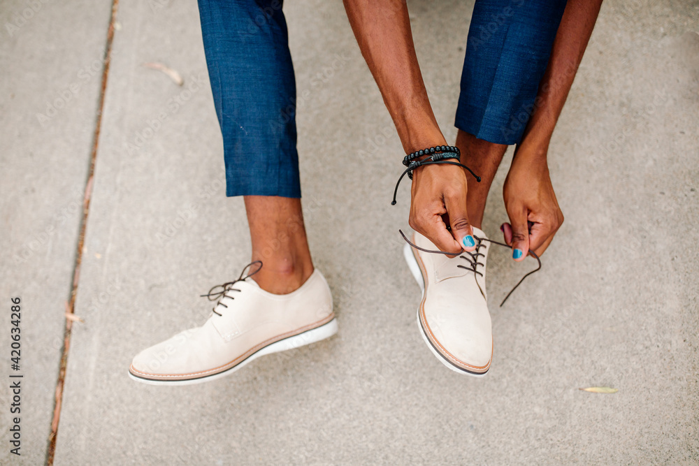 Lower legs of black male tying shoes Lower legs of black male tying shoes
