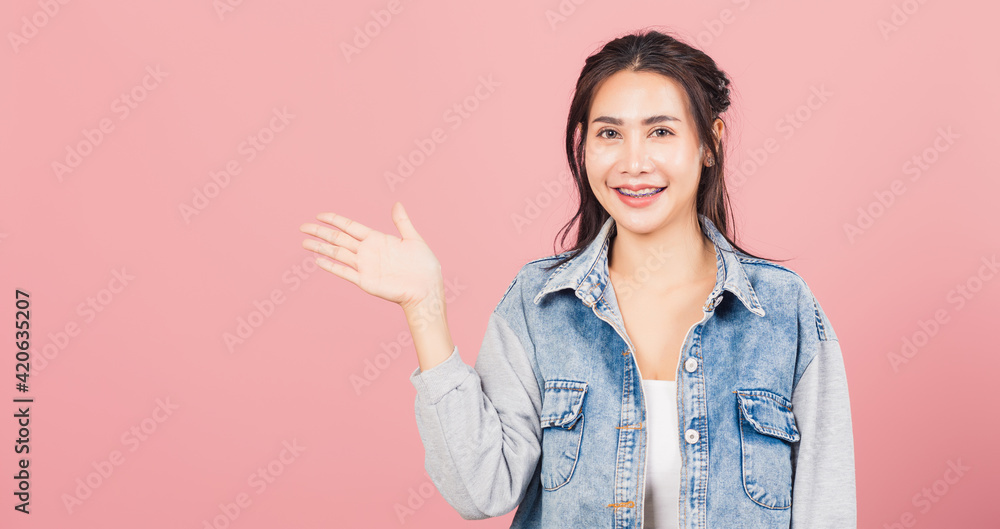 Asian happy portrait beautiful cute young woman smile standing presenting product holding something on palm away side, studio shot isolated on pink background with copy space, female show hand gesture Asian happy portrait beautiful cute young woman smile standing presenting product holding something on palm away side, studio shot isolated on pink background with copy space, female show hand gesture