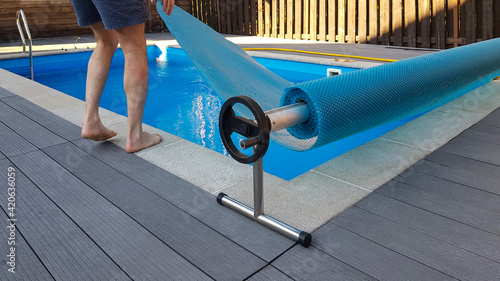 Canvas Print Man covers swimming pool with cover for protection against dirt, leaves, heating